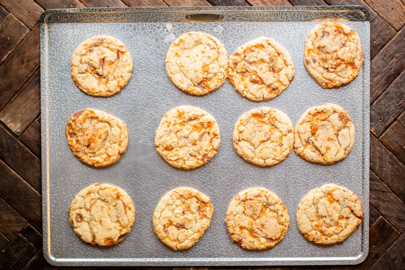 sheet pan with 12 butterfinger cookies on it.