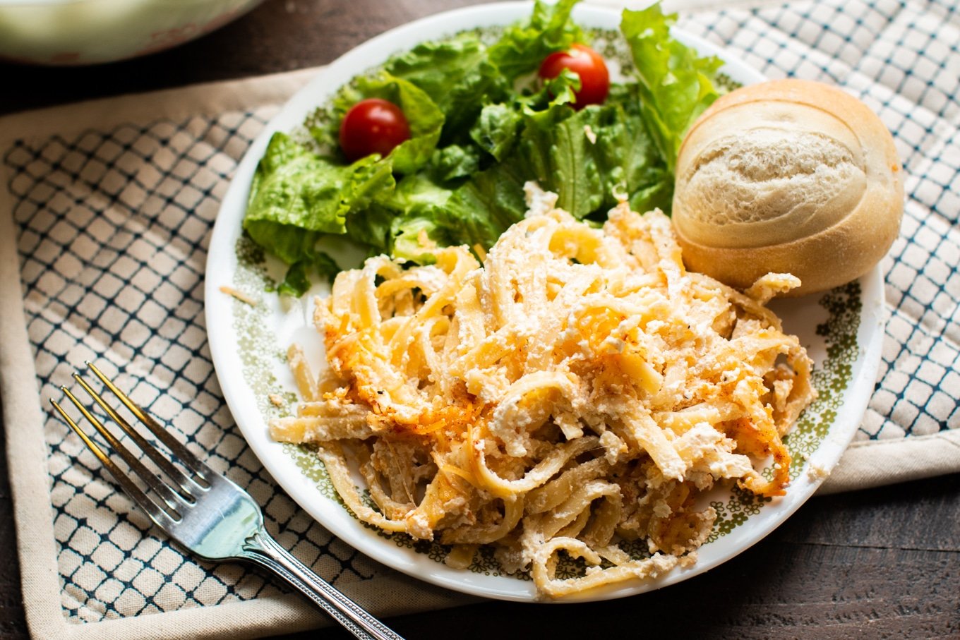 plate with salad, dinner roll and noodles romanoff