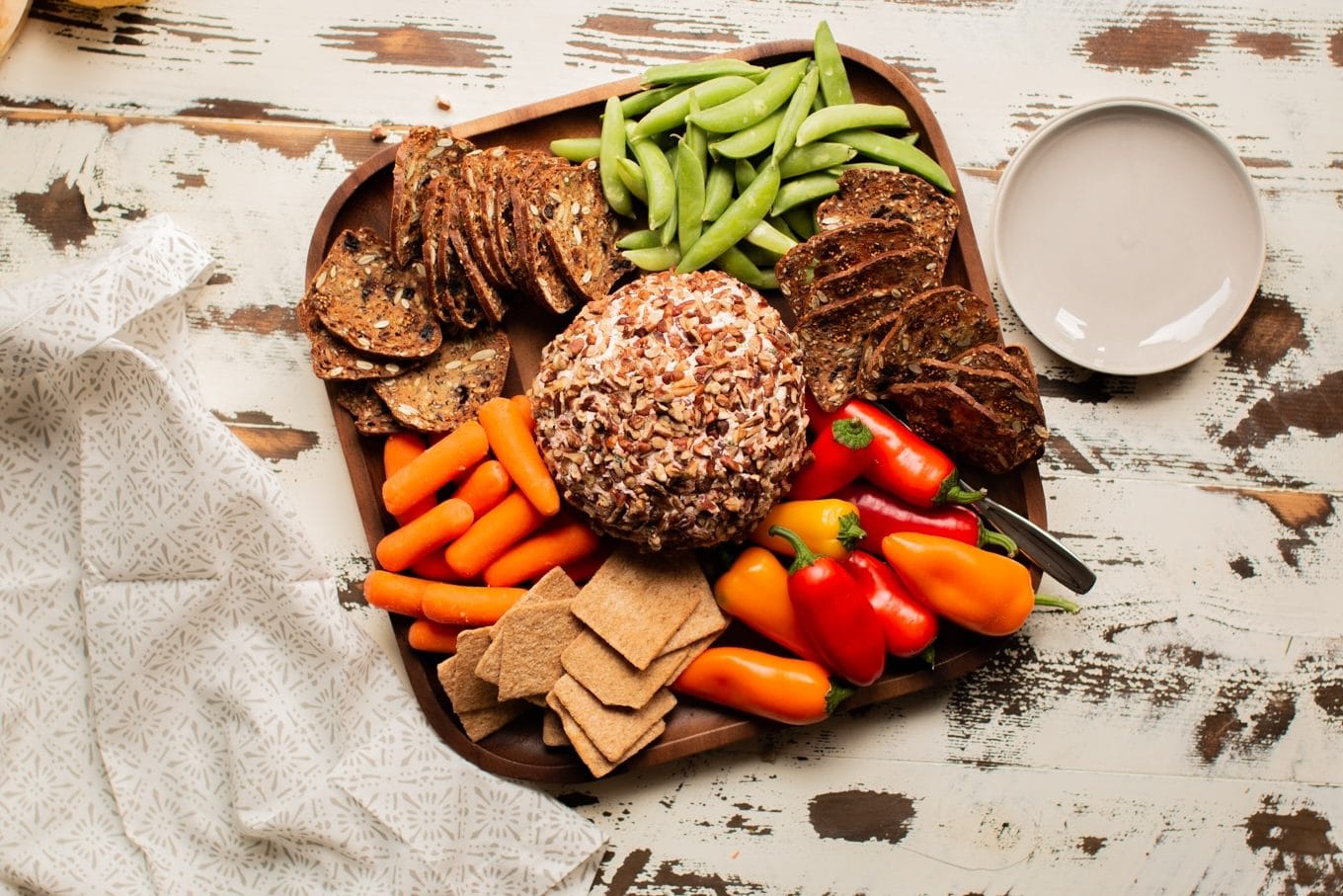 salmon cream cheese ball covered in pecans with veggies and crackers around it.