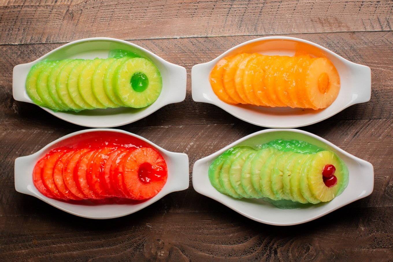 4 white boat shaped dishes with pineapple and jello

