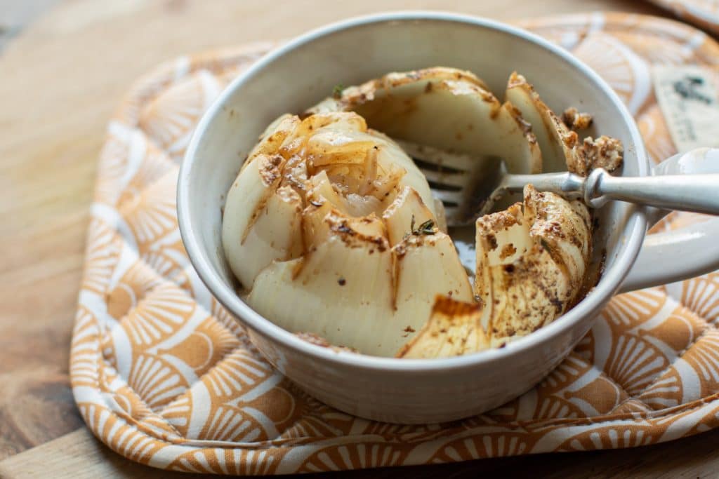 baked onion with fork in it.