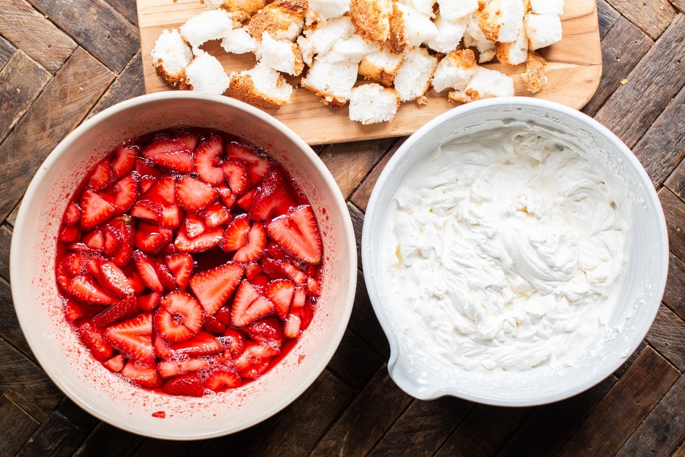 A bowl of food on a wooden table, with Strawberry and Angel food cake