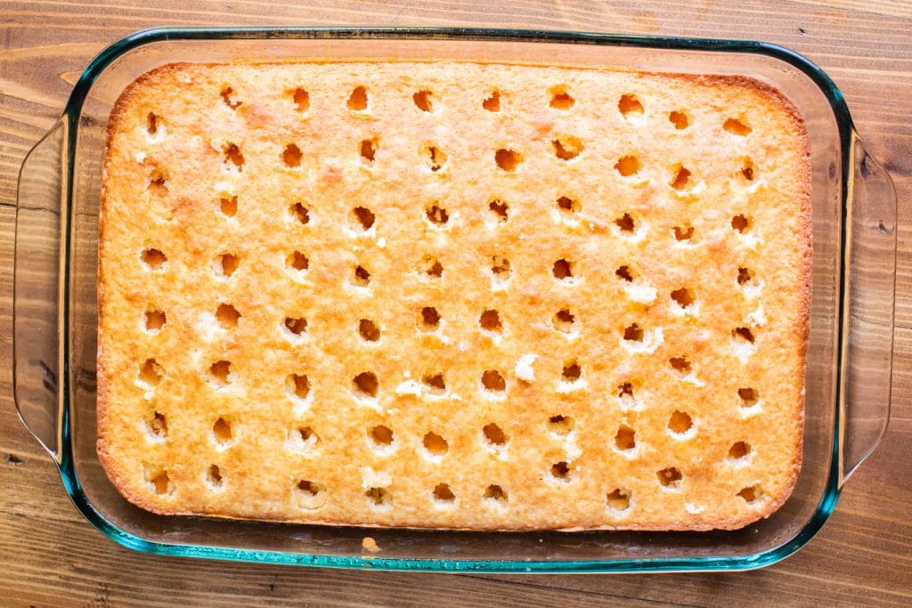 cooked white cake with holes poked in it.