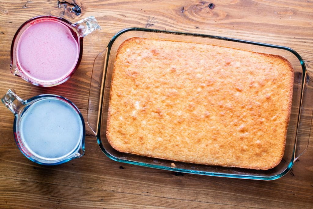 baked white cake with jello in measuring cups on the side.