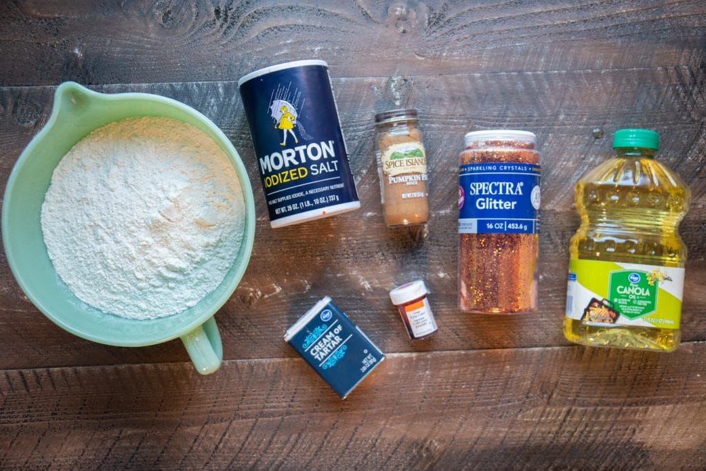 ingredients for pumpkin pie play dough on wooden table.