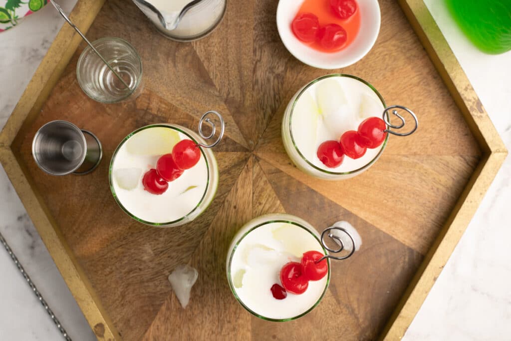 3 melon sherbet cocktails on tray with cherries