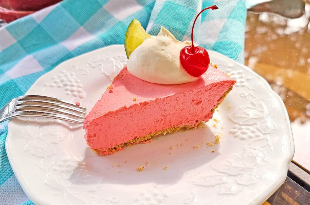 slice of cherry lime pie on plate with whipped cream and cherry