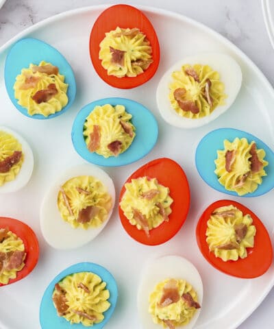 round plate of red white and blue eggs with bacon and paprika