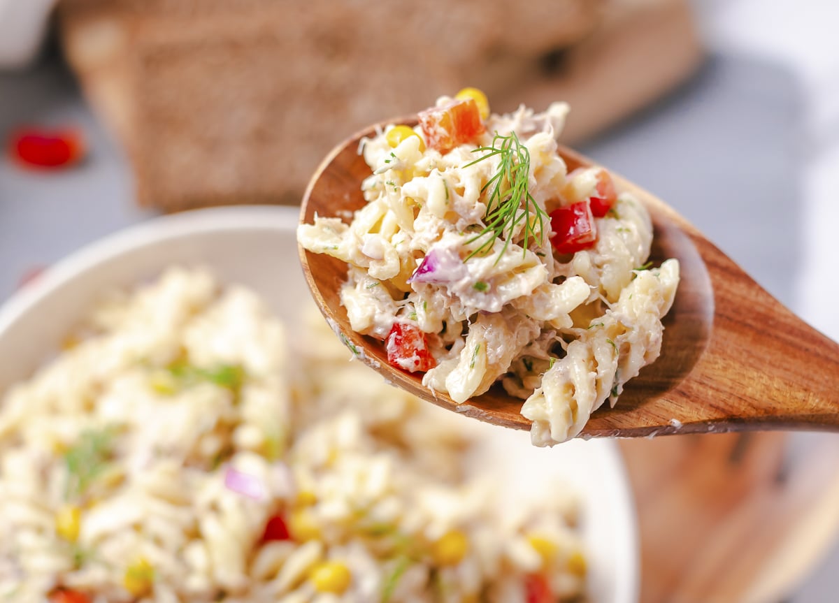 tuna pasta salad on spoon with dill on it.