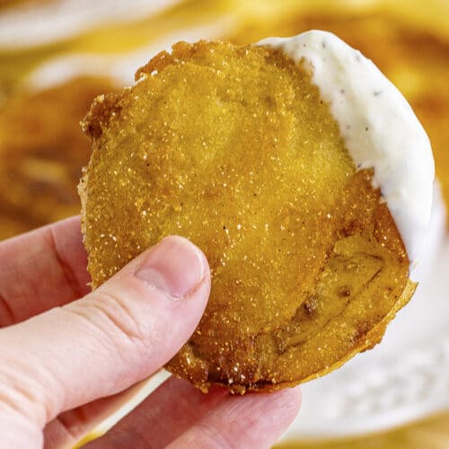close up of fried green tomato in hand with ranch.