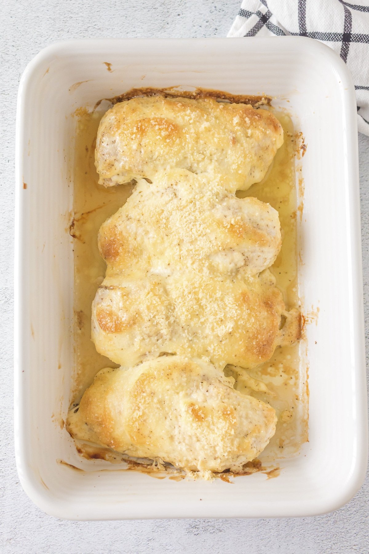 mayonnaise parmesan chicken baked in white casserole dish.