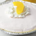 peach jello pie with whipped cream and peach on top.