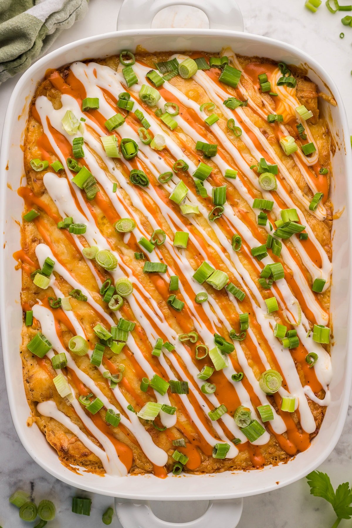 Cooked buffalo chicken enchiladas in a white pan.