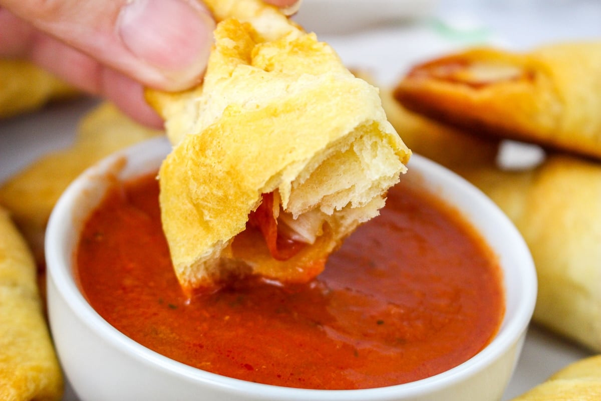 pizza roll being dipped in marinara.