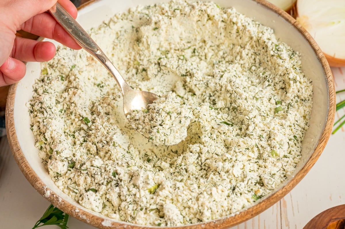A spoon scooping out some homemade ranch mix from a bowl.