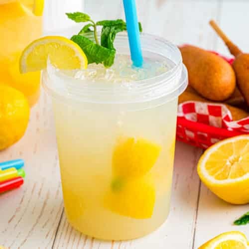 State fair lemonade in a plastic jar with a lemon slice and mint garnish on top.