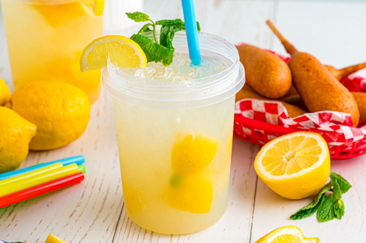 State fair lemonade in a plastic jar with a lemon slice and mint garnish on top.